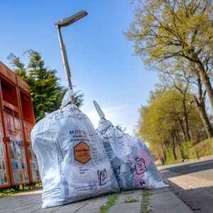Altkleidersäcke am Straßenrand vor den Sammelcontainern der Kolpingsfamilie Hollage.