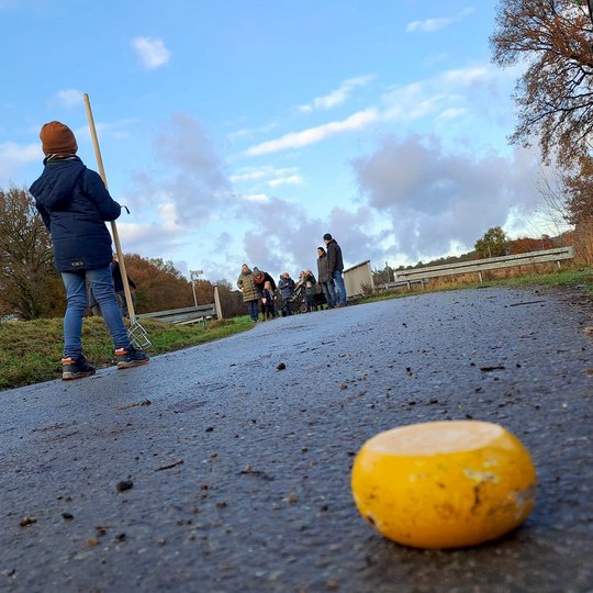 Beim Kloatscheeten wird im Gegensatz zum Boßeln nicht mit einer Kugel sondern mit einer abgerundeten Scheibe geworfen. Familien beim Kloatscheeten auf der Straße.